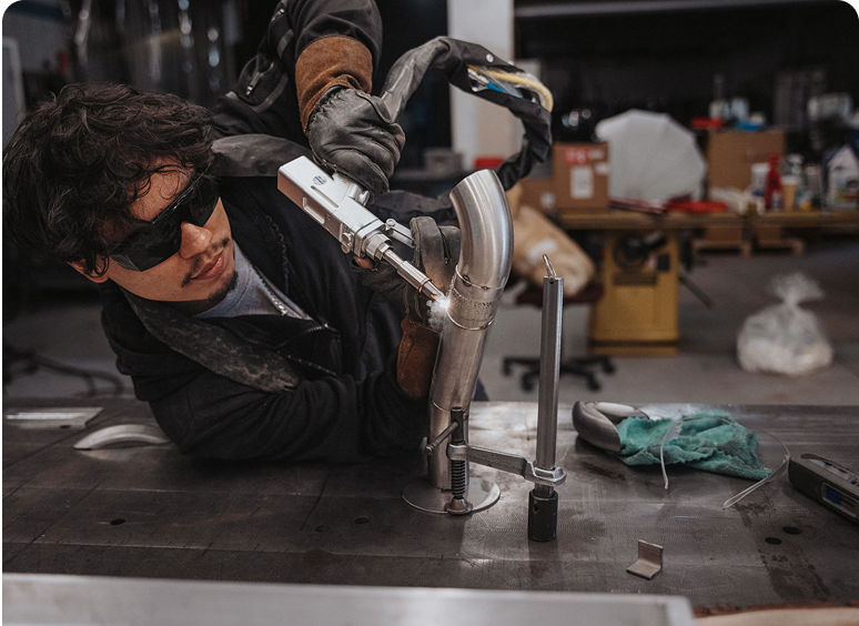 Technician welding metal pipe in workshop.