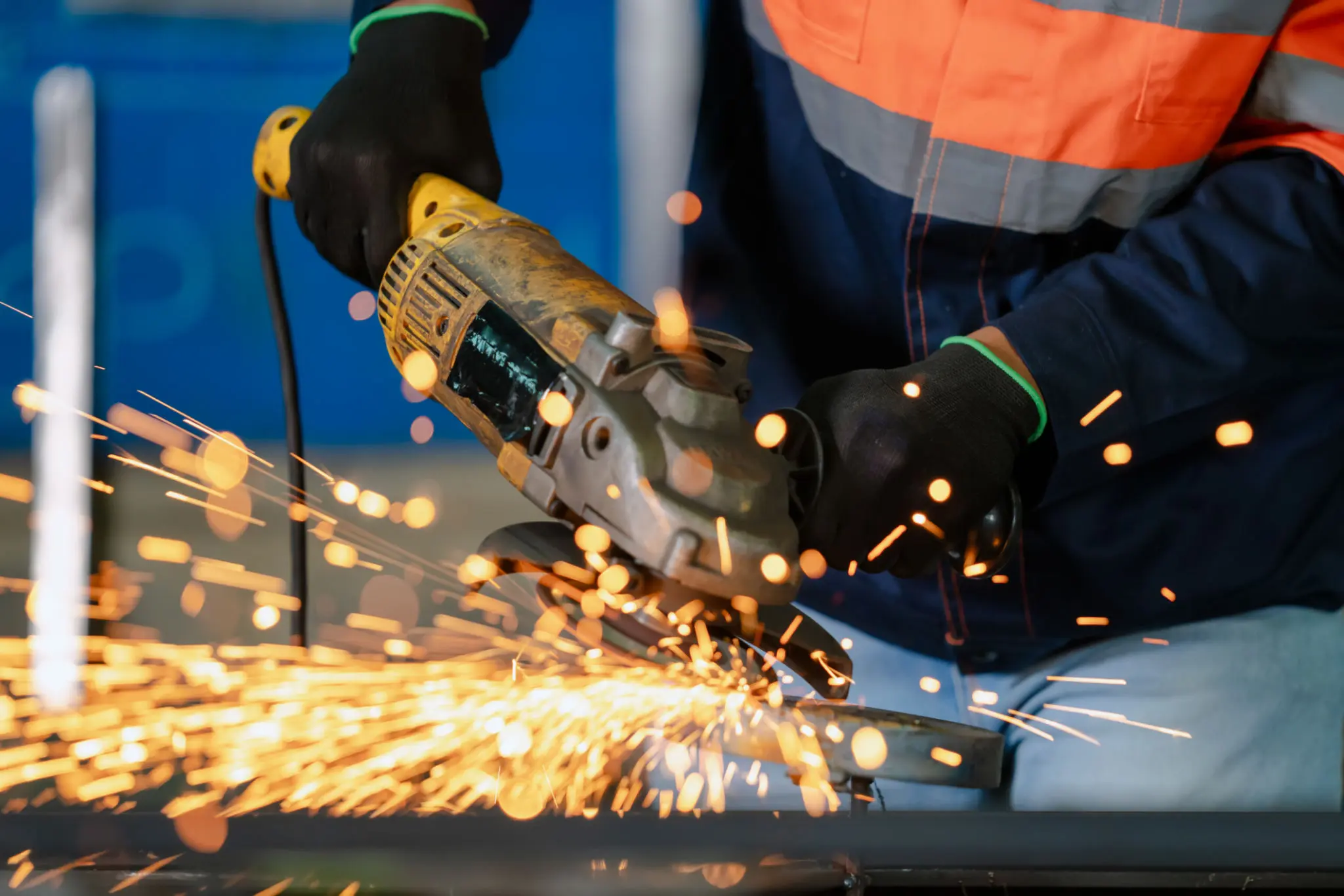 Worker using grinder, sparks flying around.