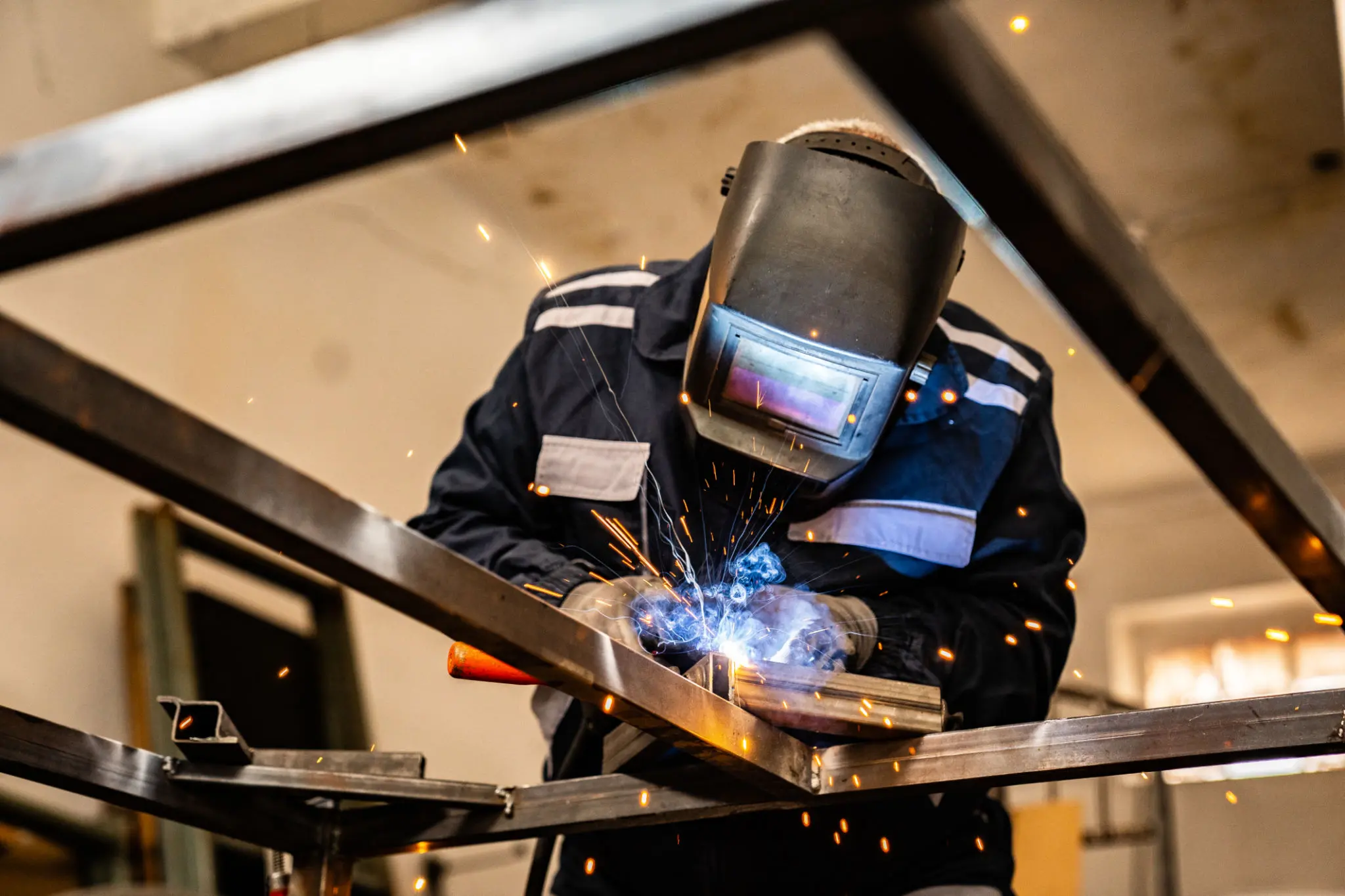 Welder working with sparks in workshop.